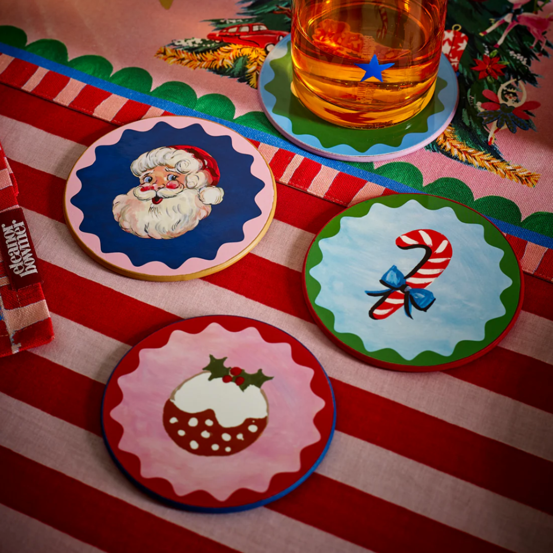 Set of Christmas-themed coasters on a striped tablecloth