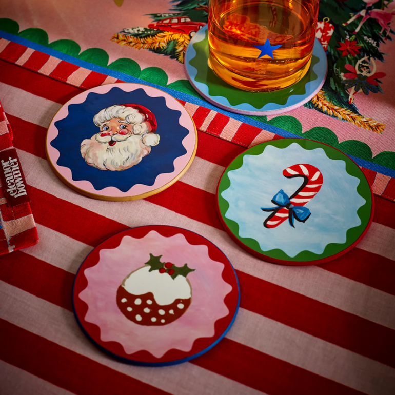 Set of Christmas-themed coasters on a striped tablecloth