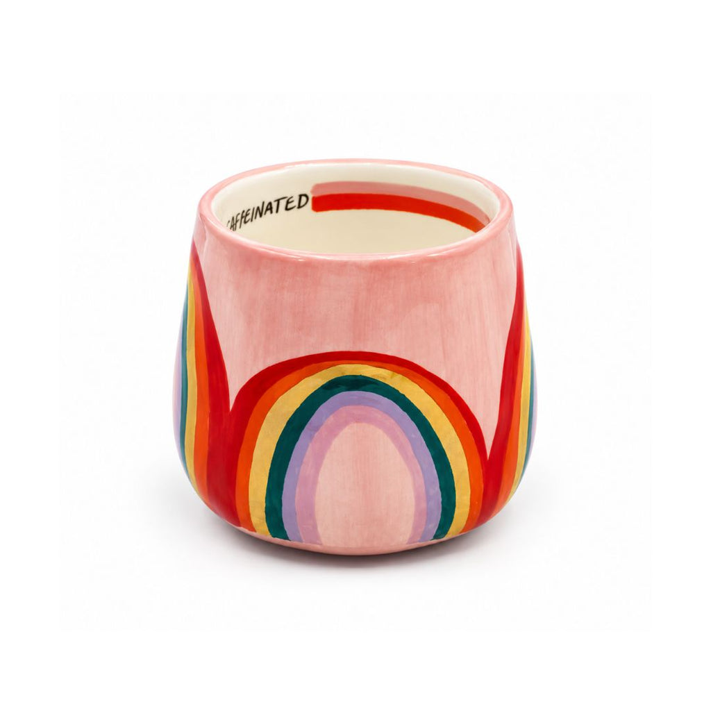 A pink ceramic cup with a retro rainbow design in red, orange, yellow, green, blue, and purple.